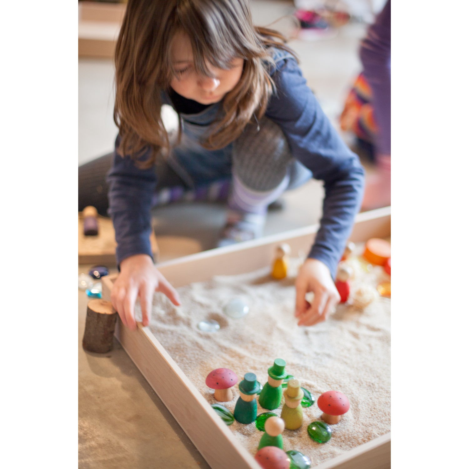 a child playing with natural items in the Grapat wooden tray box