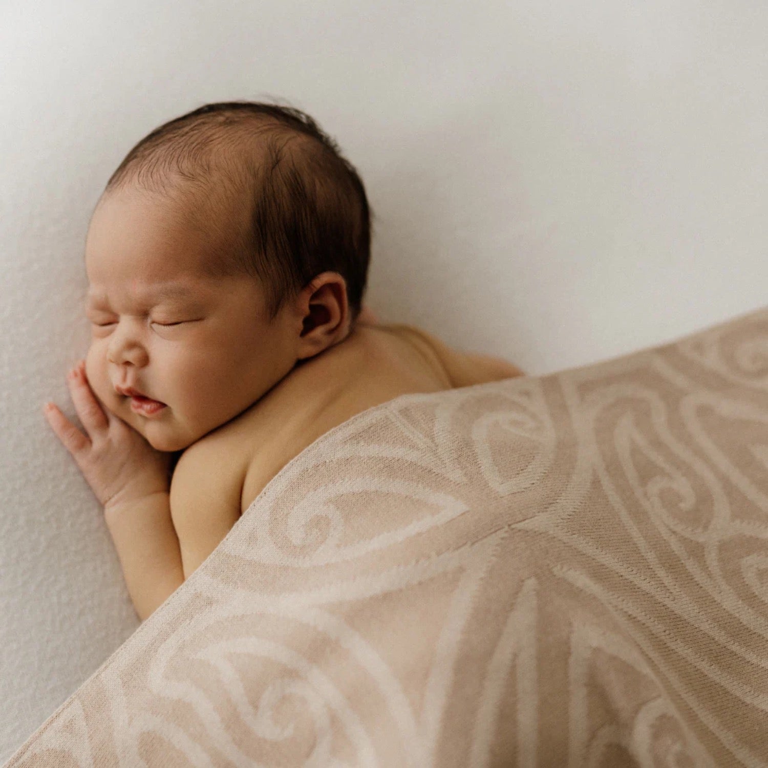 Patterned baby blanket draped over a wooden stool against a plain background