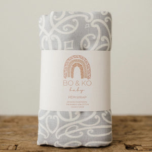 Folded baby wrap with 'Bo & Ko' label on a wooden surface
