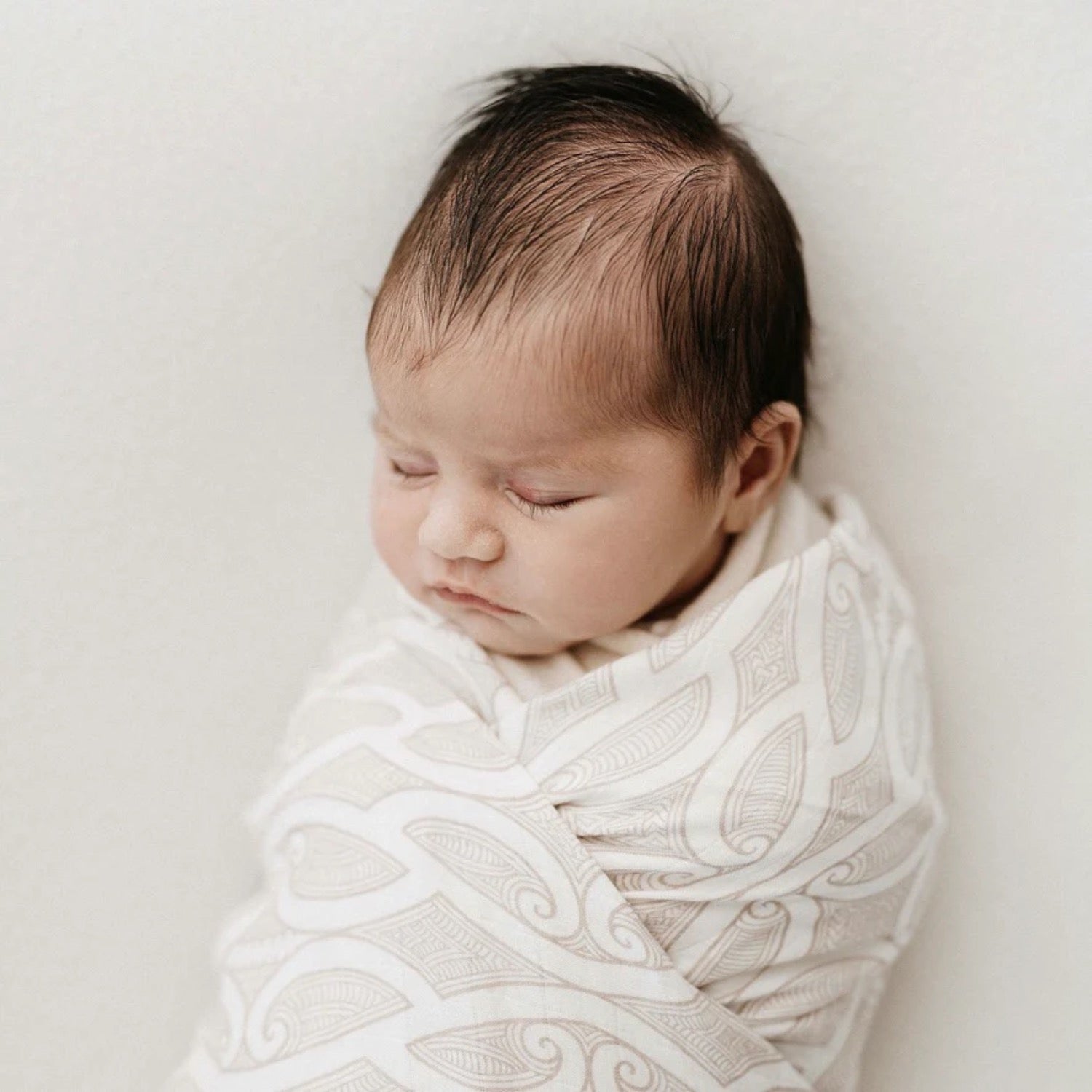 White baby wrap with intricate patterns and 'BO & KO' branding on a wooden surface.