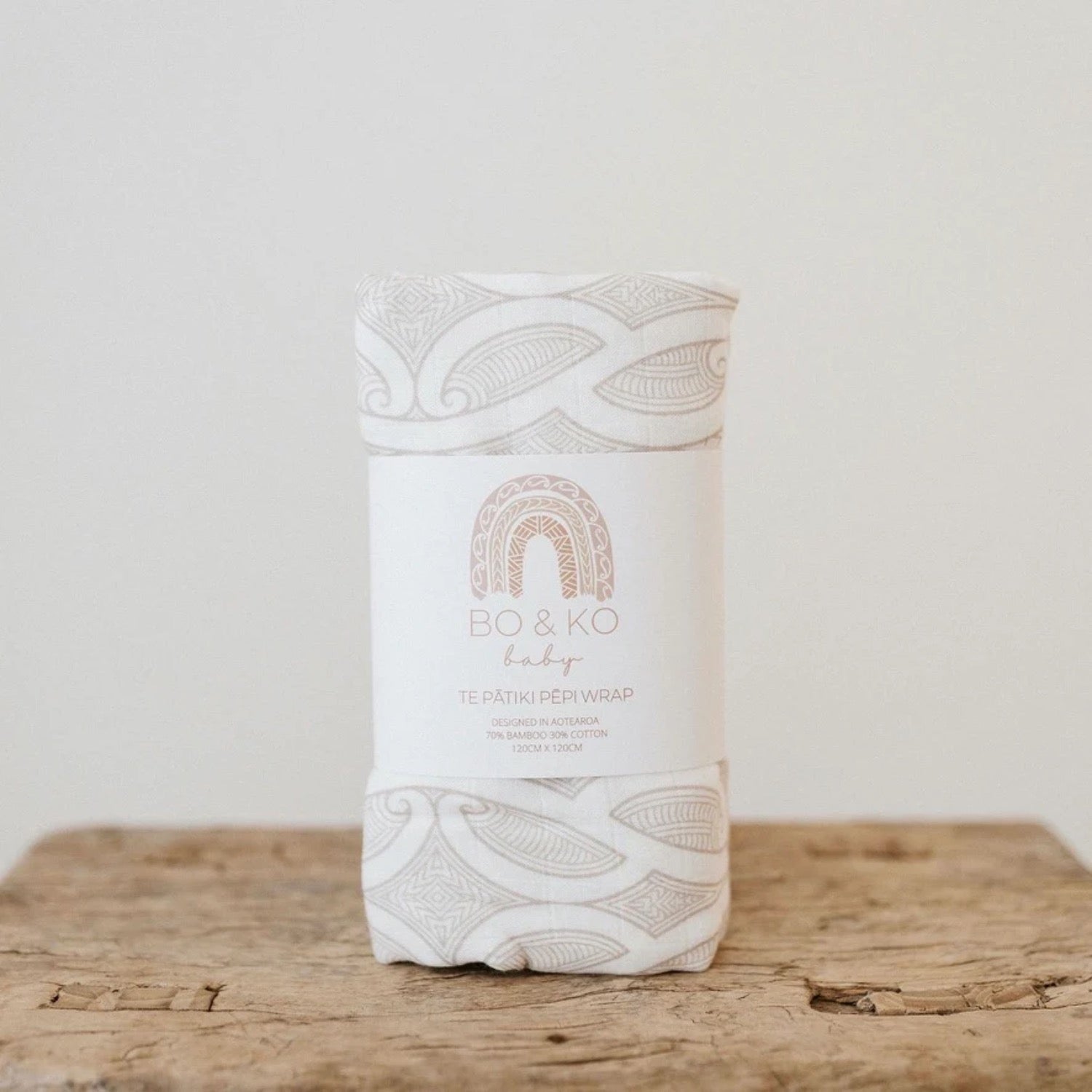 White baby wrap with intricate patterns and 'BO & KO' branding on a wooden surface.