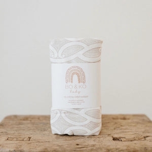 White baby wrap with intricate patterns and 'BO & KO' branding on a wooden surface.