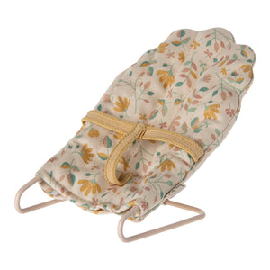 Floral-patterned baby bouncer with a yellow strap on a white background
