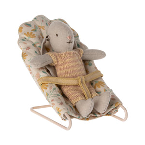 Stuffed animal in a baby bouncer with floral pattern on a white background
