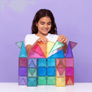 Girl playing with colorful magnetic building blocks against a purple background