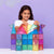 Girl playing with colorful magnetic building blocks against a purple background