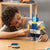 Child playing with a robot toy made of interlocking blocks on a wooden table.