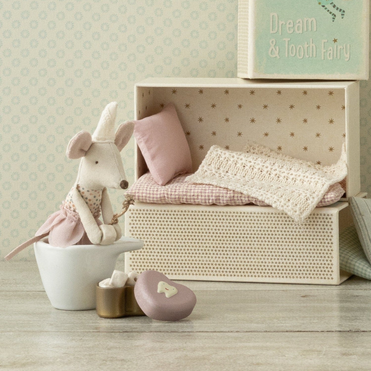 Stuffed mouse toy with a decorative box featuring illustrations and text on a white background