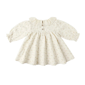 Cream-colored baby dress with subtle pattern on a white background
