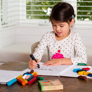 Girl sitting at desk coloring in using Honey Sticks crayons